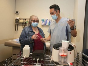 Brenda Crowell (L) speaks with interventional radiologist Dr. Jason Wong at Foothills Hospital in Calgary and is shown the Indigo Lightening CAT12 on Thursday, August 19, 2021. The new device was used on Crowell to quickly extract blood clots from her lungs in May. The device used for the first time in Canada saved Crowell's life after she developed a blood clot caused by COVID-19. Jim Wells/Postmedia