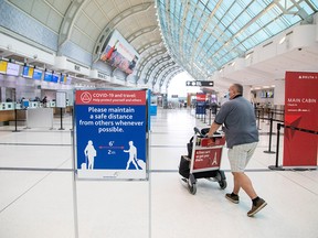 A man pushes a baggage cart wearing a mandatory face mask as a "Healthy Airport" initiative is launched for travel, taking into account social distancing protocols to slow the spread of the coronavirus disease (COVID-19) at Toronto Pearson International Airport in Toronto, Ontario, Canada June 23, 2020.  REUTERS/Carlos Osorio/File