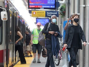 Transit users are seen wearing masks on a CTrain platform in downtown Calgary on Tuesday, Aug. 3, 2021.