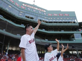 Chris Snow, an assistant general manager for the Calgary Flames, acknowledges the crowd with son Cohen and daughter Willa before throwing out a ceremonial first pitch before a baseball game between the Boston Red Sox and Tampa Bay Rays at Fenway Park, Thursday, Aug. 12, 2021, in Boston. (AP Photo/Mary Schwalm) ORG XMIT: 958a529b9f21481c9a53a179ed072b7d-958a529b9f21481c9a53a179ed072b7d-0