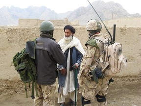 A Canadian soldier questions an Afghan elder about Taliban activity in the Panjwaii district, Afghanistan, through an Afghan interpreter on March 20, 2007.
