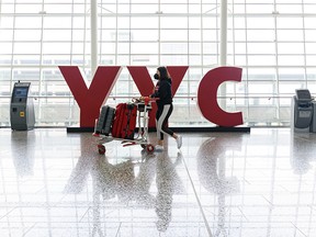 A passenger pushes baggage through the Calgary International Airport on Monday, July 19, 2021.