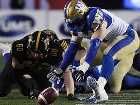 Nov 24, 2019; Calgary, Alberta, CAN; Winnipeg Blue Bombers linebacker Adam Bighill (4) recovers a fumble ahead of Hamilton Tiger-Cats offensive lineman Darius Ciraco (60) in the first half during the 107th Grey Cup championship football game at McMahon Stadium. Mandatory Credit: Eric Bolte-USA TODAY Sports ORG XMIT: USATSI-408191
