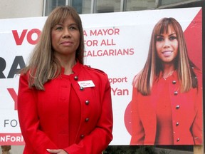 Calgary Mayoral Candidate Grace Yan poses for a photo in front of her campaign sign on 1st St. SE. Yan said she's received multiple hate-filled and racist messages during her campaign, in addition to having her signs vandalized.