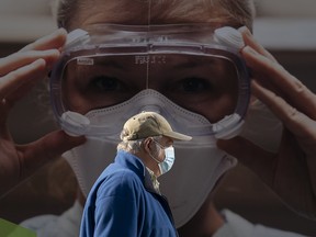 A man wears a protective face mask as he walks past a billboard from the Vancouver General Hospital on April 8, 2021.