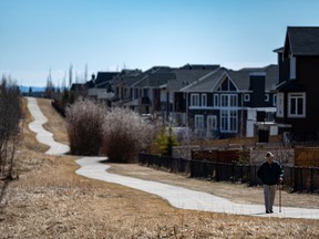 A pedestrian takes a walk on a pathway in Aspen Woods on a sunny day in Calgary on Tuesday, April 13, 2021.