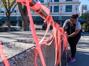 On Wednesday, September 29, 2021, Yvonne Henderson with Bear Clan Patrol Calgary attaches orange ribbons to the railings outside City Hall in preparation for September 30’s vigil on National Day for Truth and Reconciliation.