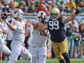 CHICAGO, ILLINOIS - SEPTEMBER 25: Rylie Mills #99 of the Notre Dame Fighting Irish rushes against Cormac Sampson #62 and Graham Mertz #5 of the Wisconsin Badgers at Soldier Field on September 25, 2021 in Chicago, Illinois. Notre Dame defeated Wisconsin 41-13.