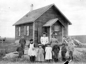 Schoolhouses were a crucial part of life on the prairies decades ago. Here, a school group is pictured at , Red Deer Lake school. L-R back row: Bertie Lloyd (small boy in front); Ralph Lloyd, behind; Hermione Lloyd (girl wearing tam); Miss Hawkey, teaching (later Mrs. William Edgar); Gertrude Lloyd (girl wearing large hat).
L-R front row: Norman McArthur (blurred figure); Jessie McArthur (wearing plaid dress); Elizabeth Bell; Edric Lloyd; Ronald Lloyd; Gordon McArthur.
Date: circa 1900-1903   Photo: Courtesy, Glenbow Archives; NA-2568-1.