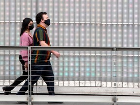 Masked people are seen walking along the 4th St. SW Bridge. Thursday, September 30, 2021.