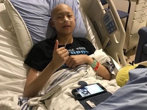 Julian Ho give a thumb's up from his bed at the Alberta Children's Hospital. Photo courtesy of Ho family.