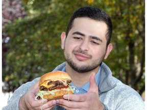 Farbod Jahanshah enjoys a burger from Alumni Sandwiches along 17th Avenue S.W. Jahanshah put his business school skills to the test by creating a rating system of Calgary's dowtown burger joints. Brendan Miller/Postmedia