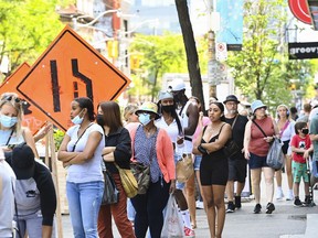 People shop and wait in long lines to enter stores along Queen Street West during the COVID-19 pandemic in downtown Toronto on June 11, 2021.