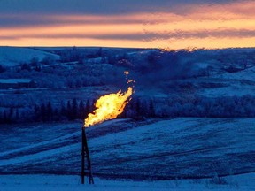 A natural gas flare on an oil well pad burns as the sun sets outside Watford City, North Dakota.