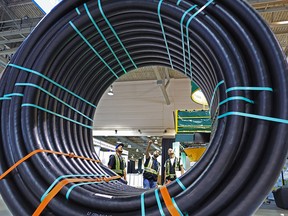 Workers check out a spool of pipe on display at the FlexSteel booth at the Global Petroleum Show in Calgary in 2018. The annual event — now called the Global Energy Show — has been postponed to 2022 due to rising COVID numbers.