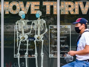 A masked cyclist rides past a window display at a chiropractic centre in Calgary on Wednesday, Sept. 8, 2021.