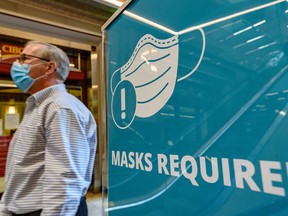 A man walks by a sign requiring people to wear a mask at Bankers Hall in downtown Calgary on Monday, Sept. 13, 2021.