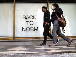 Pedestrians walk past a Hudson's Bay store window sign in downtown Calgary on Tuesday, Aug. 31, 2021.