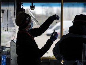 Volunteer health-care workers conduct tests on a rapid COVID-19 screening bus in the Waterloo Region on April 30, 2021.