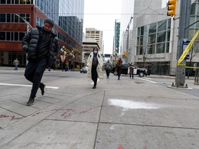 People walk around the blood trail left at the scene of a stabbing that took place earlier in the morning in downtown Calgary on Friday, Oct. 15, 2021.