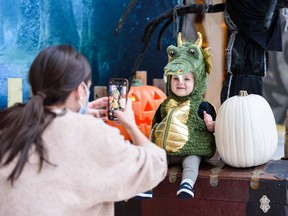 One-year-old Emmitt, dressed as a dragon, sits for a photo by his mom (not pictured) at one of the five Halloween-themed photo backdrops in Southcentre Mall on Wednesday, October 20, 2021. Before opening hours on Halloween the five trick or treat stations and a sensory-friendly environment will be available for families with special needs children to have an inclusive Halloween gathering at Southcentre Mall.