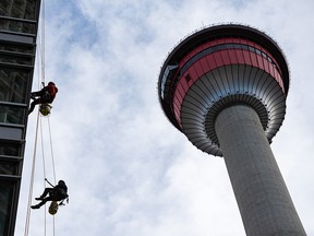 Window cleaners work on a building facing the Calgary Tower on Monday, October 25, 2021.