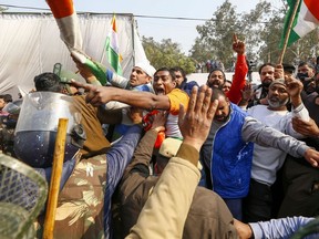 Police try to stop local residents as they clash with farmers who continue their protest against the central government's recent agricultural reforms blocking a highway at the Delhi-Haryana state border in Singhu on January 29, 2021.