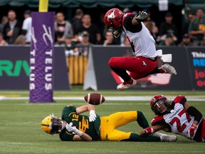 The Calgary Stampeders’ Branden Dozier jumps over the Edmonton Elks’ Mike Jones at Commonwealth Stadium in Edmonton on Saturday, Sept. 11, 2021.