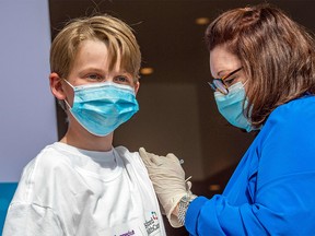 Charles Muro, age 13, is inoculated by Nurse Karen Pagliaro at Hartford Healthcare's mass vaccination center at the Connecticut Convention Center in Hartford, Connecticut on May 13, 2021.