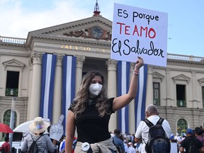 A woman holds a poster that reads "It's because I love you El Salvador" during a demonstration against the circulation of Bitcoin and other economic measures, as well as a decree that removed judges from their functions, in San Salvador, on October 17, 2021.