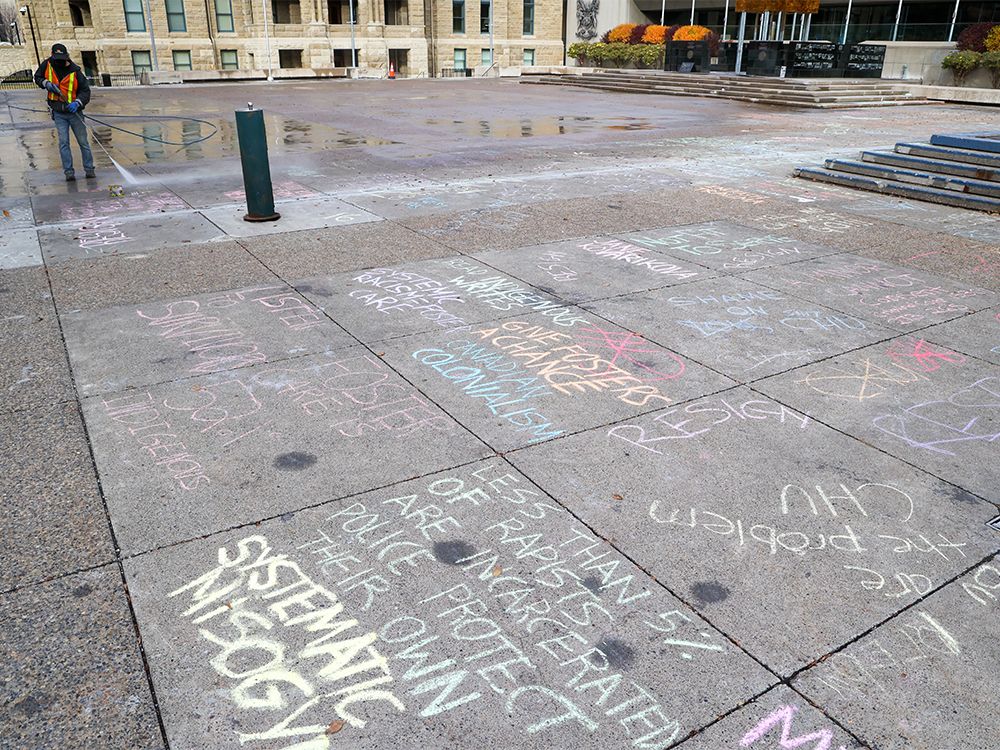  A worker washes off chalk messages calling on Ward 4 councillor Sean Chu to resign in front of Calgary City Hall following protests on Sunday, October 24, 2021.
