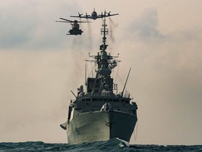 A CH-148 Cyclone helicopter and a CP-140 Aurora maritime patrol aircraft fly over the Royal Canadian Navy frigate HMCS Winnipeg as part of a photo exercise in the Asia-Pacific Region in November 2020.