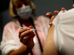 FILE PHOTO: A medical worker administers a dose of the "Comirnaty" Pfizer BioNTech COVID-19 vaccine in a vaccination center in Nantes, France, September 14, 2021.