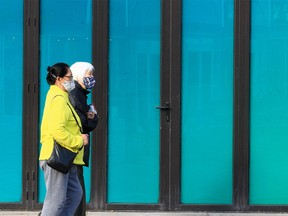 People wearing masks are seen walking along 17th Ave SW. Thursday, October 28, 2021.