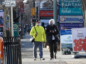 People wearing masks are seen walking along 17th Ave SW. Thursday, October 28, 2021.