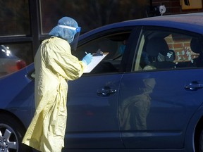 A health care worker takes information for a COVID-19 test from a driver at the Richmond Road Diagnostic and Treatment Centre on Oct. 4, 2021.
