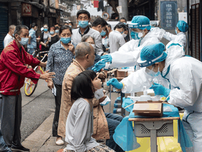Medical workers take swab samples from residents to be tested for the COVID-19 coronavirus, in a street in Wuhan on May 15, 2020.