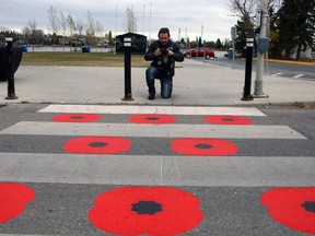 Veteran Andy Sinclair, who served 29 years as a flight engineer with the Canadian Forces, takes a photo of a crosswalk painted with poppies in Chestermere. Sinclair is happy to see the crosswalk but the Legion says people walking over the poppies is disrespectful and wants to see the flowers removed.