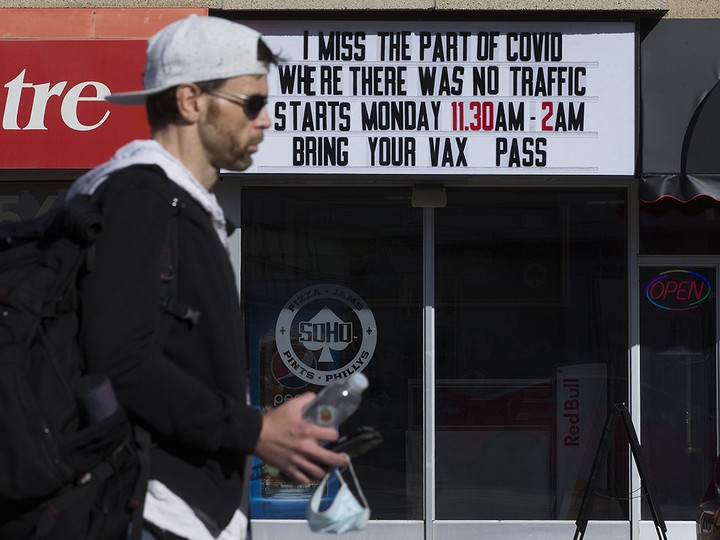  A pedestrian passes a COVID-19 sign outside SOHO pub on Jasper Avenue in Edmonton, Thursday, Sept. 23, 2021.