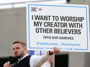 Tobias Tissen, minister at Church of God Restoration near Steinbach, holds a sign as he speaks during an anti-mask rally at The Forks in Winnipeg on Sun., April 25, 2021.
