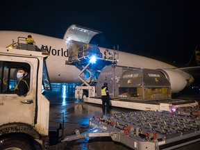 Airport ground crew offload a plane carrying the first shipment of the Pfizer-BioNTech COVID-19 vaccine, approved for children aged five to 11, in Hamilton, Ont., Sunday, Nov. 21, 2021.