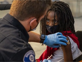 Jeremiah Mack, 9, prepares to receive a Pfizer-BioNtech COVID-19 vaccine from firefighter Luke Lindgren on November 3, 2021 in Shoreline, Washington.