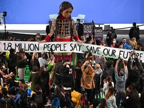 Little Amal, a giant puppet depicting a Syrian refugee girl, holds a banner reading '1.8 Million People Say: Save Our Future Now' during COP26 on Nov. 9, 2021 in Glasgow, Scotland.