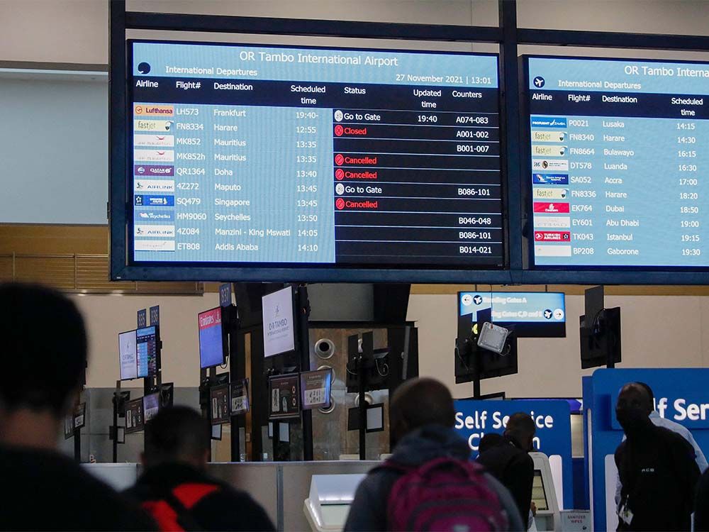  Travellers walk near an electronic flight notice board displaying cancelled flights at OR Tambo International Airport in Johannesburg on November 27, 2021, after several countries banned flights from South Africa following the discovery of a new COVID-19 variant Omicron.