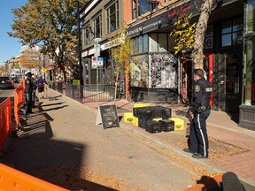 Calgary Bylaw officers supervise the seizure of property in front of Without Papers Pizza including a sign that said “We Serve All" on October 7, 2021.