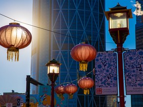 Lanterns and lights light up in morning light with The Bow tower as a backdrop in Calgary’s Chinatown on Wednesday, November 24, 2021.