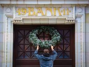Lyndon Strandquist places a Christmas wreath above the entrance to Teatro Restaurant in downtown Calgary on Nov. 25, 2021.