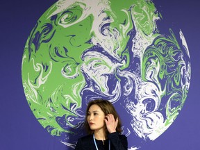 A delegate stands next to a banner during the UN Climate Change Conference (COP26) in Glasgow, Scotland, Britain, November 1, 2021.