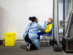 An employee of the Public Health Service of the Netherlands (GGD) carries out a test for Covid-19 in a street testing centre in the Hague, on November 17, 2021.