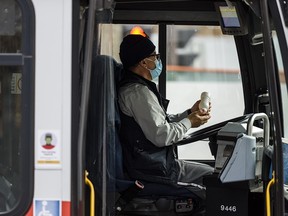 A transit bus driver sanitizes his hands during a stop in downtown Calgary on Nov. 6, 2020.